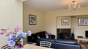 Ein Wohnzimmer mit einer Couch, einem Tisch mit Blumenvase, einem Kamin und einer Kristallleuchter.