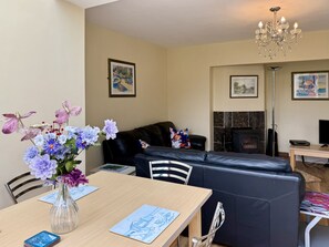 Ein Wohnzimmer mit einer Couch, einem Tisch mit Blumenvase, einem Kamin und einer Kristallleuchter.