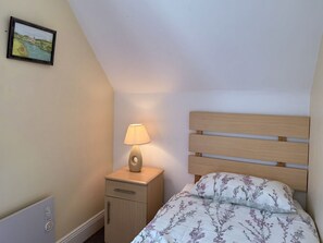 Ein Schlafzimmer mit einem Bett, einem Nachttisch mit Lampe, einem Wandbild und einer Heizung.