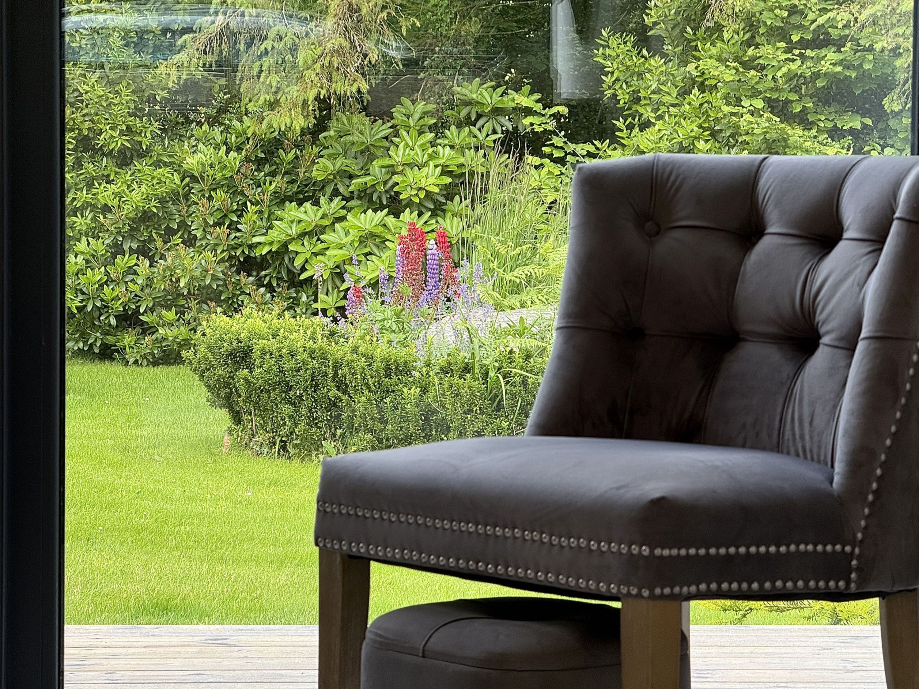 A single dark-colored upholstered chair with a cushioned seat and backrest, positioned on a wooden deck.