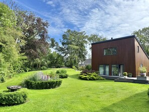 Een modern huis met twee verdiepingen, een verzorgd gazon en een tuin.
