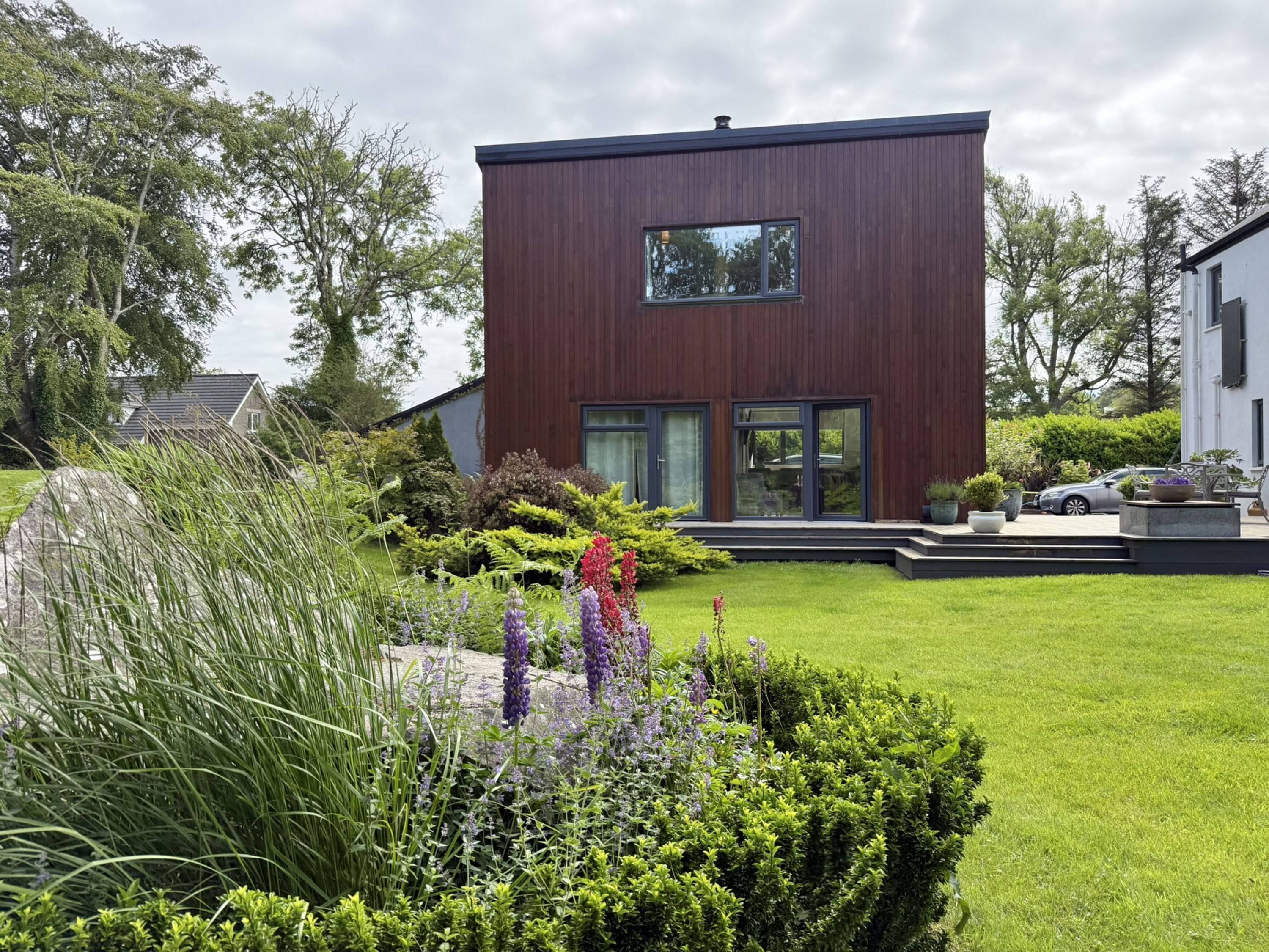 Una moderna casa a due piani con un prato e un giardino curati.