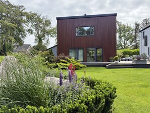 Una casa moderna de dos pisos con un césped y jardín bien cuidados.