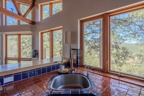 A kitchen with a large window, a sink, and a countertop. - Mountain Retreat in the Sangre de Cristo Foothills (Santa Fe)