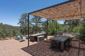 Eine Terrasse im Freien mit einer Pergola, Sitzgelegenheiten und Grillplatz.