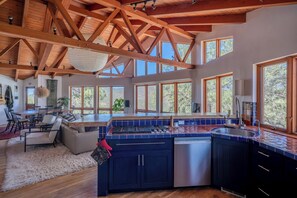 A spacious kitchen with a large island, wooden beams, and large windows. - Mountain Retreat in the Sangre de Cristo Foothills (Santa Fe)