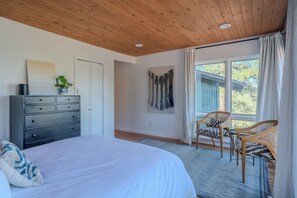 Een slaapkamer met een bed, een dressoir en stoelen bij een raam.
