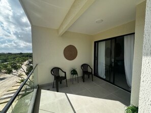 A balcony with two chairs, a small table, and a potted plant. - Cozy 2BR Condo | Pool | FREE Electricity (Punta Cana)