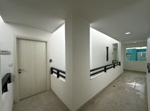 A hallway with a door labeled '402' and a handrail on the right side. - Cozy 2BR Condo | Pool | FREE Electricity (Punta Cana)