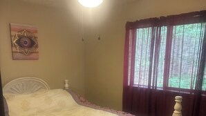 A bedroom with a bed, a ceiling fan, a window with curtains, and a wall decoration. - Shady Leaf Lodge - Family and pet-friendly! Arrowhead Lake getaway (Pocono Lake)