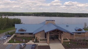 A building with a blue roof, a stone facade, and a parking lot with cars.
