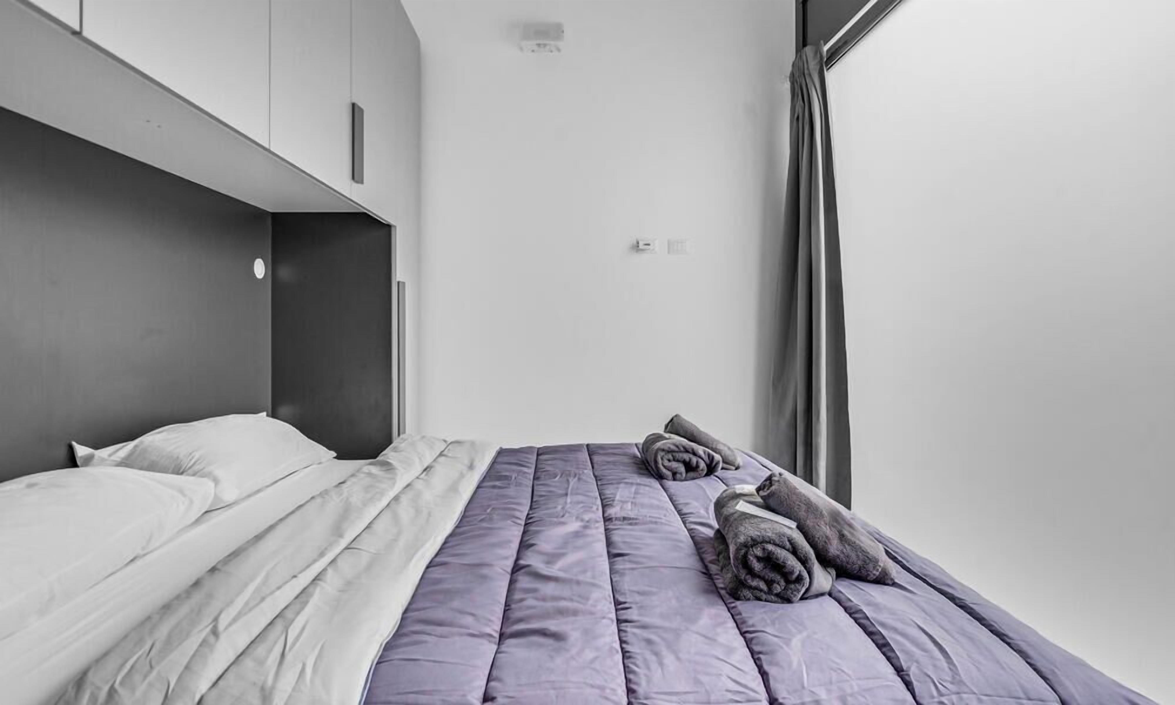 A modern bedroom with a bed, pillows, and a folded towel.