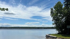 A sandy beach with footprints, a clear sky, and a tree line in the distance. - The sundowner #5 Private Beach (Kawartha Lakes)