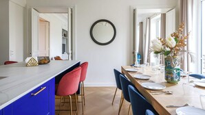 A dining area with a long table, chairs, and a vase with flowers. - Luxurious Apartment - 4br/10p- Ternes/pereire (Paris)