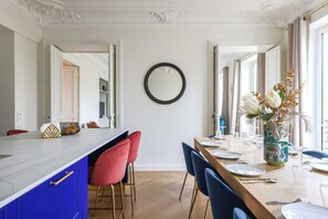 A dining area with a long table, chairs, and a vase with flowers. - Luxurious Apartment - 4br/10p- Ternes/pereire (Paris)