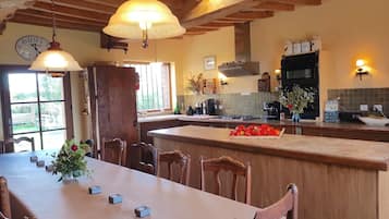 Une cuisine dotée d’un îlot central, de chaises en bois, d’une table à manger et de luminaires suspendus.