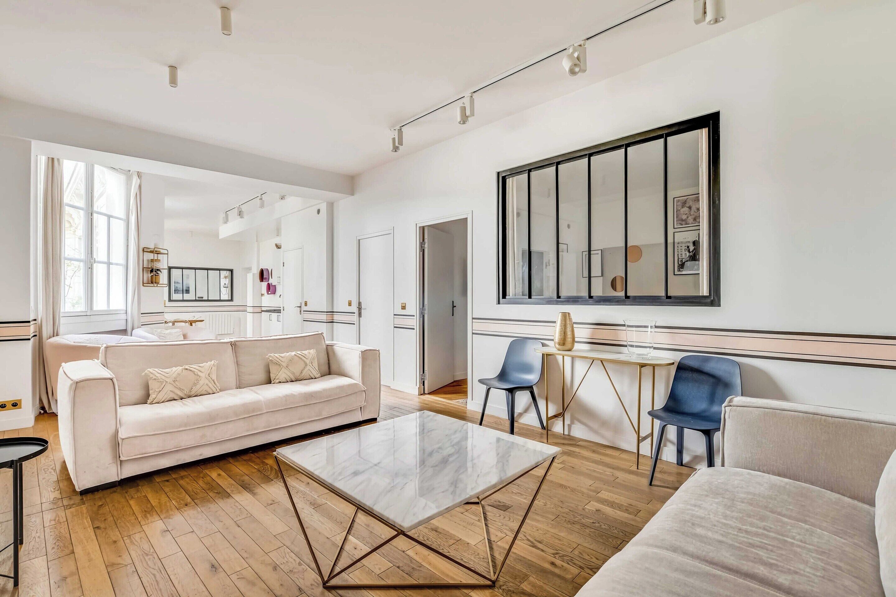 Un salon moderne avec un canapé, une table basse et des fauteuils.