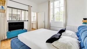 A bedroom with a bed, a TV, and a window with curtains. - Modern Flat - 2ch/6p - Bastille (Paris)