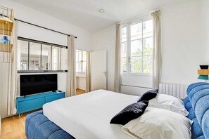 A bedroom with a bed, a TV, and a window with curtains. - Modern Flat - 2ch/6p - Bastille (Paris)
