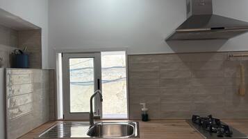 Una cocina con un lavamanos de acero inoxidable, una estufa a gas y una ventana con vistas al exterior.