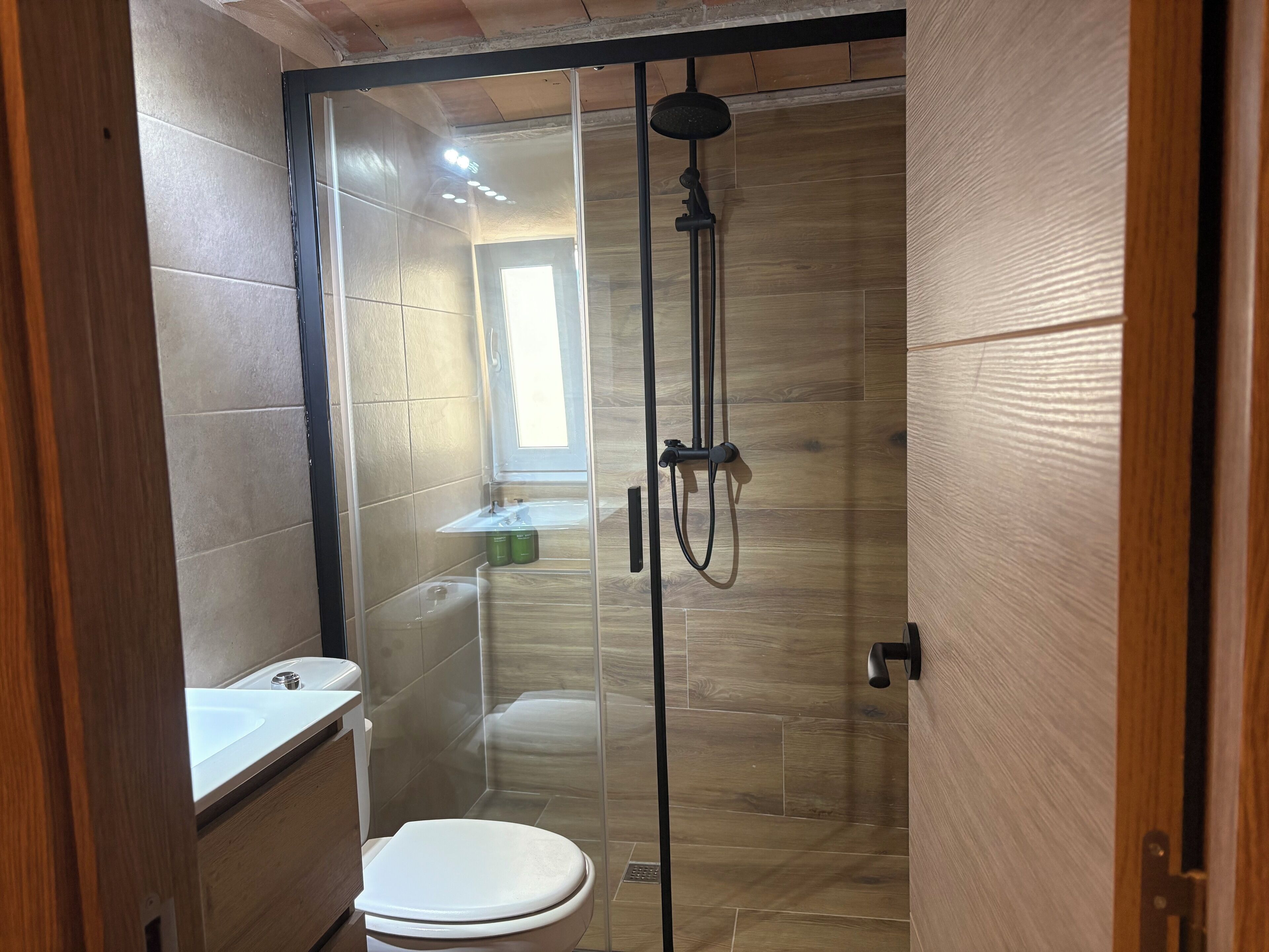 Een badkamer met douche, toilet en wastafel.