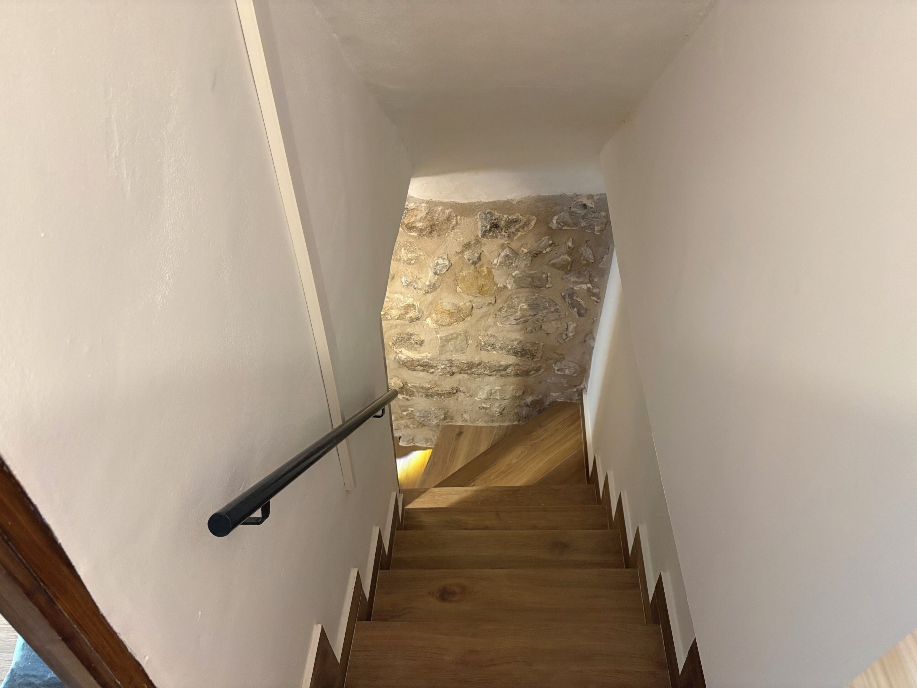A staircase with wooden steps and a stone wall at the top.