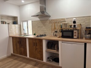 Una cocina moderna con armarios de madera, campana extractora de acero inoxidable, microondas y lavavajillas.