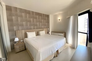 A modern hotel room with a large bed, a bedside table, a nightstand, and a window with curtains. - SHB Melhor prédio com vista para o mar (Santos)