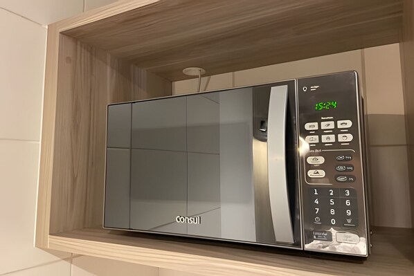 Un microondas con pantalla digital y teclado, integrado en un mueble con marco de madera.