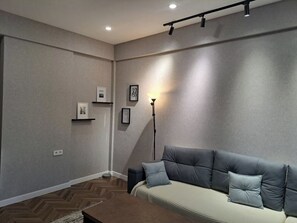 A modern living room with a sofa, a floor lamp, and framed pictures on the wall. - Arbat Premium Apartment in central Bishkek (Bishkek)