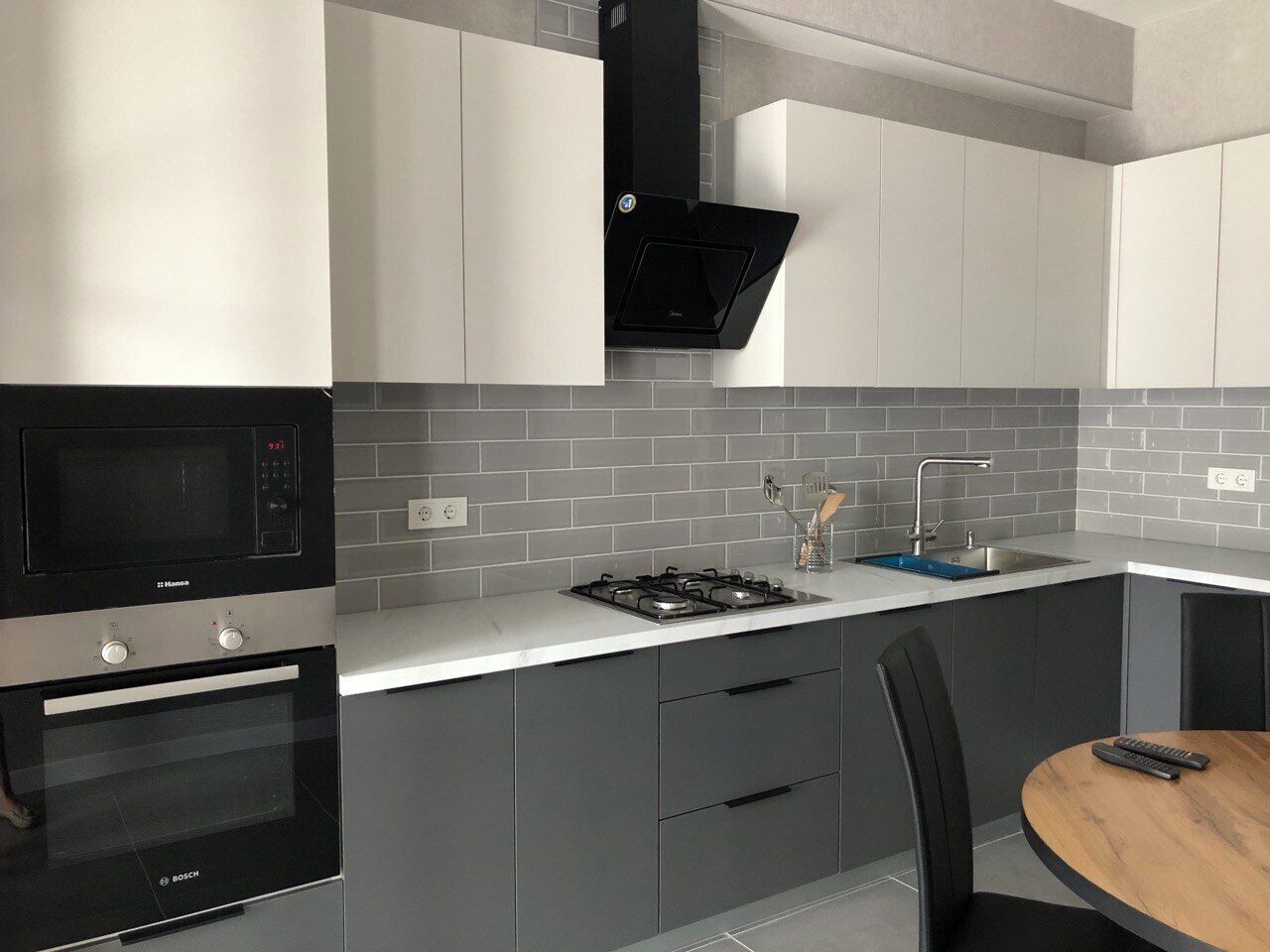 Una cucina moderna con forno a microonde integrato, forno, piano cottura a gas e lavello.