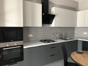 A modern kitchen with a built-in microwave, oven, gas stove, and a sink. - Arbat Premium Apartment in central Bishkek (Bishkek)
