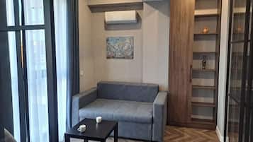 A modern living room with a grey sofa, a small table, and a wall-mounted air conditioner.
