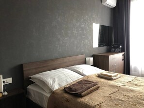 A hotel room with a bed, a wooden headboard, a nightstand, a lamp, a dresser, and a mirror. - Arbat Premium Apartment in central Bishkek (Bishkek)