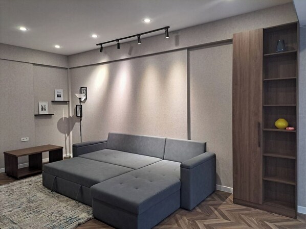 Una sala moderna con un sofá seccional, una lámpara de pie y una estantería empotrada de madera.