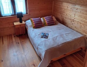 A wooden room with a bed, a nightstand, and a window. - Comfortable Holiday Home Very Close to the Beach (Ustronie Morskie)