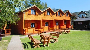 A row of wooden cabins with picnic tables and a paved walkway. - Holiday Home With a Terrace, Close to the Beach (Ustronie Morskie)