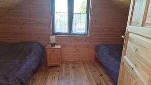 A small, wooden-paneled room with two beds, a nightstand, and a window. - Holiday Home With a Terrace, Close to the Beach (Ustronie Morskie)