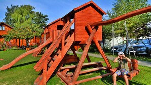 A wooden structure resembling a house with a swing attached to it. - Holiday Home With a Terrace, Close to the Beach (Ustronie Morskie)
