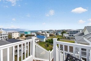 Un quartier résidentiel situé sur la côte, avec de nombreuses maisons, un ciel dégagé et une vue sur l’océan.