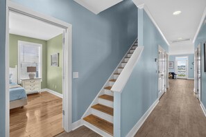 A hallway with a staircase, wooden flooring, and light blue walls. - Canal Views, Saltwater Pool, Private Elevator (Carolina Beach)
