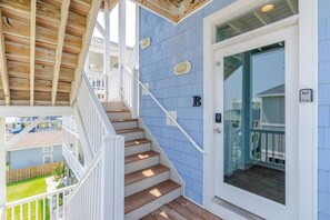 A residential property with a wooden staircase, a blue exterior, and a glass door. - 5BR Heated pool Oct-Nov, sunset views, near beach (Carolina Beach)