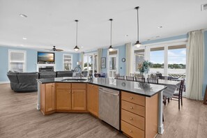 A modern kitchen with a large island, wooden cabinets, and pendant lighting. - 5BR Heated pool Oct-Nov, sunset views, near beach (Carolina Beach)