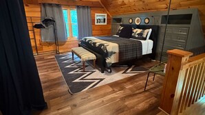 Un dormitorio tipo cabaña de madera con cama, banco y cómoda.