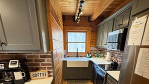 Una cocina funcional con vigas de madera, un lavamanos, una estufa y un refrigerador.