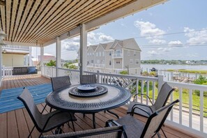 A covered outdoor area with a round table and chairs, overlooking a body of water and buildings. - 2 Kitchens, heated pool thru Nov, near beach (Carolina Beach)