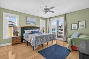 A bedroom with a bed, bedside table, lamp, ceiling fan, and a view of the outside. - 2 Kitchens, heated pool thru Nov, near beach (Carolina Beach)