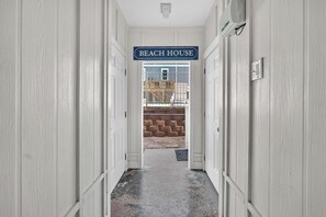 A hallway leading to a door labeled 'BEACH HOUSE' with a view of a construction site in the background. - Canal sunset views, private saltwater pool, steps to beach (Carolina Beach)
