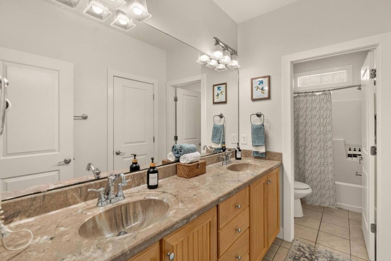 A bathroom with a double sink vanity, a large mirror, and a shower area.