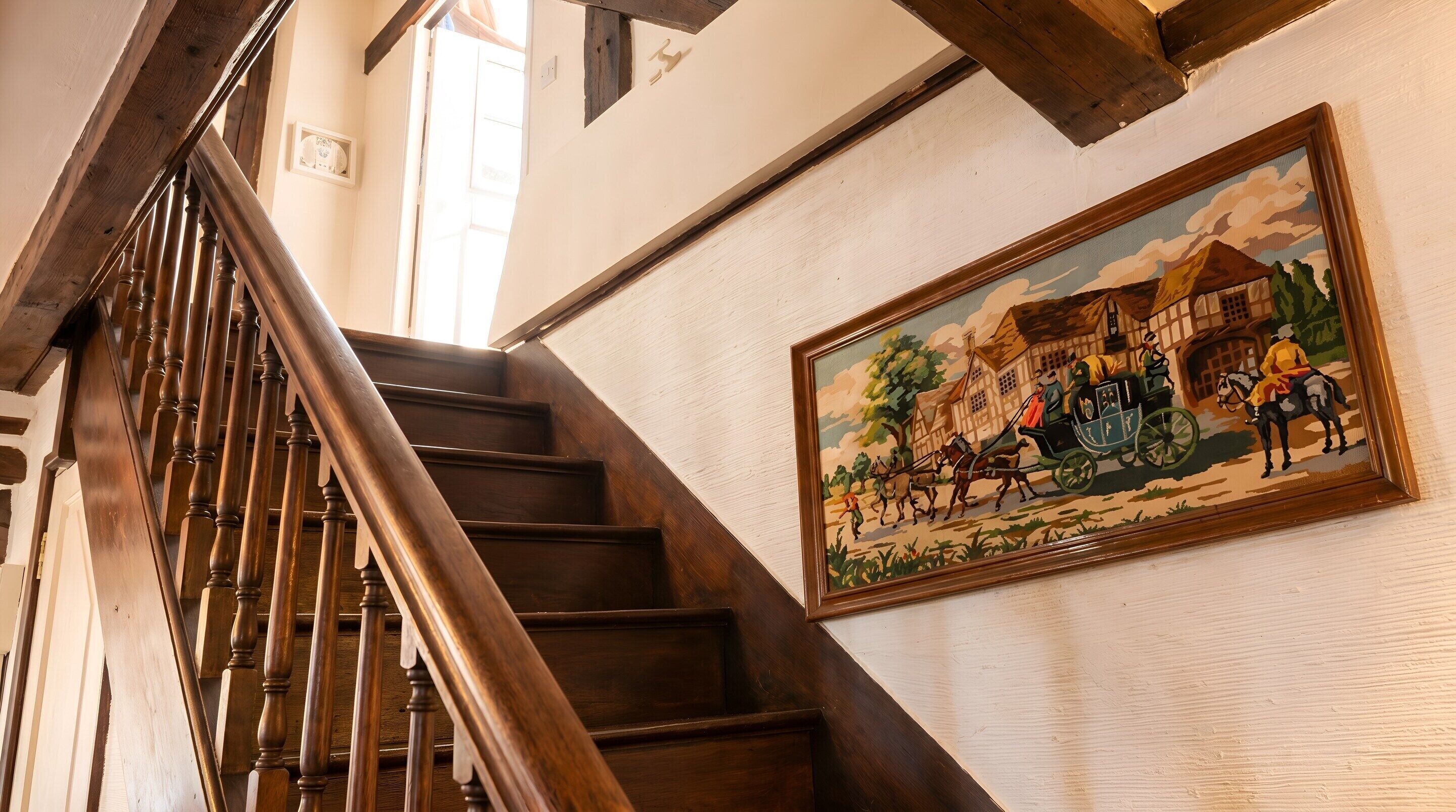 Un escalier en bois orné d’un tableau représentant une scène historique.